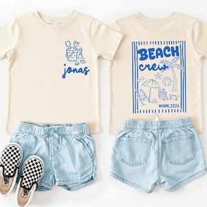 personalized beach kids shirt with front graphic and back design featuring beach elements and custom name location and year for vacation outfit