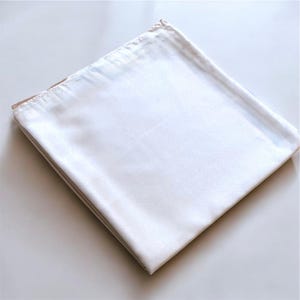 May include: A white cotton fabric sheet folded in thirds. The sheet is smooth and wrinkle-free.