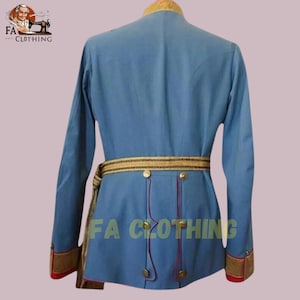Peut inclure: Veste de style militaire bleu clair avec garniture dor&eacute;e sur le col, les poignets et la ceinture. La veste a des boutons dor&eacute;s et une ceinture d&eacute;corative. Le texte "FA CLOTHING" est imprim&eacute; sur la veste.