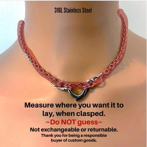The image is a close-up of a red necklace with a heart-shaped clasp, accompanied by a warning message about the necklace's clasping mechanism.