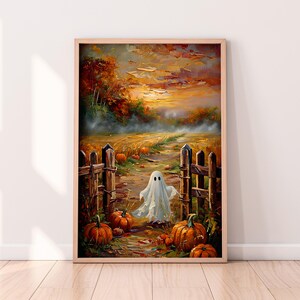 May include: A framed painting with a Halloween theme. A white ghost figure stands in a field with pumpkins, a wooden fence, and a path leading to a sunset. The artwork features warm autumn colours and a whimsical style.