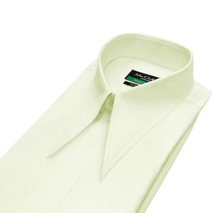 May include: A pale yellow dress shirt with a wide collar, folded neatly. The shirt has a buttoned collar and a tag that reads "John Cloth London Green". The shirt is made of a smooth fabric.