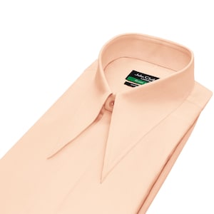May include: A pale peach dress shirt with a pointed collar, buttoned at the neck. The shirt is neatly folded, with the label "John Cloth London" visible on the collar.