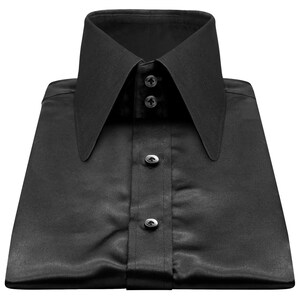 Può includere: Camicia nera piegata con colletto alto e a punta. La camicia ha una finitura satinata e tre bottoni visibili sul davanti. Il colletto è abbottonato al collo. La camicia è ben piegata.
