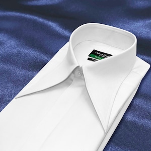 Puede incluir: Una camisa de vestir blanca y nítida con un cuello ancho y puntiagudo y una parte delantera abotonada. La etiqueta interior del cuello muestra el texto John Cloth London y Green. La camisa presenta un diseño limpio, estructurado y definido.