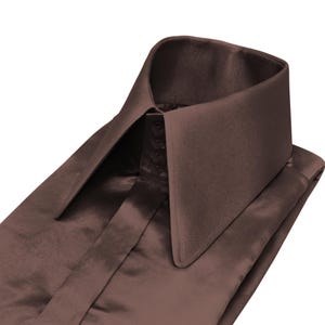 May include: A close-up of a brown satin dress shirt. The shirt has a high, pointed collar and a buttoned placket. The fabric has a subtle sheen, giving it an elegant and formal appearance.