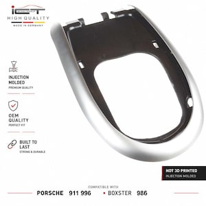 Op de afbeelding: Een zilveren en zwarte versnellingspook-omlijsting voor auto's met een glad, gebogen frame. Tekst op de afbeelding bevat ICT HIGH QUALITY MADE IN GERMANY, INJECTION MOLDED, OEM QUALITY, BUILT TO LAST, NOT 3D PRINTED, en PORSCHE 911 996 BOXSTER 986.