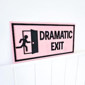 May include: Pink and black sign with a running figure silhouette and the text "Dramatic Exit".
