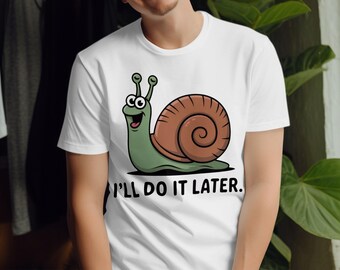 May include: White t-shirt featuring a cartoon snail with a brown shell and green body. The snail has a smiling face and the text "I'LL DO IT LATER." is printed below the snail. The shirt is a casual wear item.