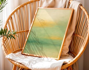 Könnte beinhalten: Ein gerahmter abstrakter Kunstdruck mit Holzrahmen, der ein Aquarelldesign in Gelb-, Grün- und Blautönen zeigt. Das Kunstwerk wird auf einem Korbstuhl mit weißem Kissen und beigem Überwurf präsentiert, mit Schatten von Blättern.