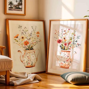 Puede incluir: Dos impresiones enmarcadas de pinturas de acuarela que representan arreglos florales en teteras vintage. Las teteras están decoradas con lunares blancos y rosas. Las flores son una mezcla de rosa, naranja y amarillo.
