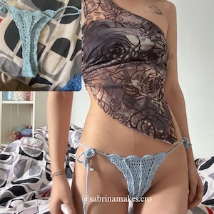 Puede incluir: Braguita de bikini de ganchillo azul claro con lazos laterales. La braguita tiene un dise&ntilde;o de borde festoneado. Una braguita de bikini de ganchillo azul claro a juego se muestra sobre una colcha estampada. Se ve el identificador de Instagram @sabrinamakes.cro.