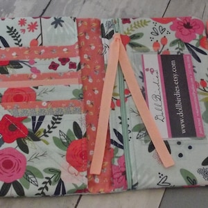 May include: A floral patterned fabric wallet with multiple card slots, a zipper closure, and a pink ribbon. The wallet has a business card holder with the text "DollBirdies" and "www.dollbirdies.etsy.com".