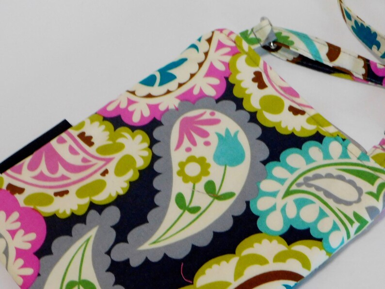 K&ouml;nnte beinhalten: Eine kleine Handtasche mit Paisley-Muster auf dunkelblauem Hintergrund und abnehmbarem Trageriemen. Das Muster ist in den Farben Pink, Gr&uuml;n, Wei&szlig; und Blau gehalten.