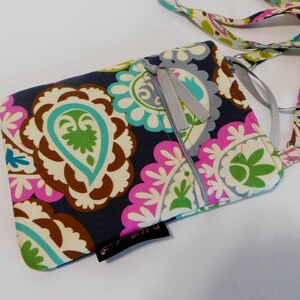 K&ouml;nnte beinhalten: Eine kleine, dunkelblaue Umh&auml;ngetasche mit Paisley-Muster in Rosa-, Gr&uuml;n- und Wei&szlig;t&ouml;nen. Die Tasche hat einen Rei&szlig;verschluss und einen silbernen Kettenriemen.