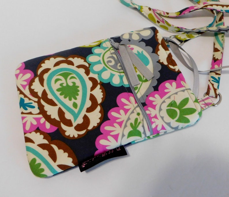 K&ouml;nnte beinhalten: Eine kleine, dunkelblaue Umh&auml;ngetasche mit Paisley-Muster in Rosa-, Gr&uuml;n- und Wei&szlig;t&ouml;nen. Die Tasche hat einen Rei&szlig;verschluss und einen silbernen Kettenriemen.