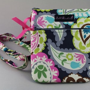 K&ouml;nnte beinhalten: Eine kleine, dunkelblaue Umh&auml;ngetasche mit Paisley-Muster in den Farben Pink, Gr&uuml;n, Wei&szlig; und Braun. Die Tasche hat einen Rei&szlig;verschluss und einen rosa Schleifenriemen. Die Tasche hat ein Etikett mit der Aufschrift "Bell Birdies".