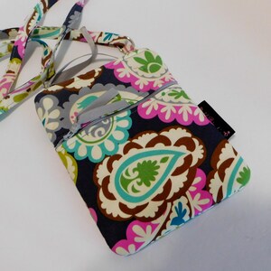 K&ouml;nnte beinhalten: Eine kleine Umh&auml;ngetasche mit Paisley-Muster, Rei&szlig;verschluss und langem verstellbarem Trageriemen. Die Tasche ist aus dunkelblauem Stoff mit verschiedenen Farben, darunter Pink, Gr&uuml;n und Braun.