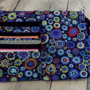 May include: A black fabric wallet with a colorful pattern of blue, green, and red circles. The wallet has multiple card slots and a zippered pocket.