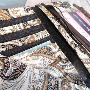 May include: Open wallet with a paisley pattern in cream, brown, and black. The wallet has multiple card slots and a zippered compartment. A brown ribbon and a business card are visible inside. The text "www.dollbirdies.etsy.com" is printed on the business card.