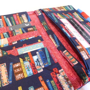 May include: A blue fabric zippered pouch with a red lining and a book print design. The pouch has multiple pockets and a clear plastic card holder with the text "www.dollbirdies.etsy.com".