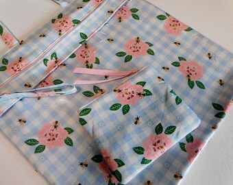 May include: A blue and white gingham tote bag with pink flowers and bees. The bag has a matching zippered pouch.