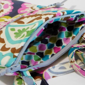 K&ouml;nnte beinhalten: Eine kleine, farbenfrohe Umh&auml;ngetasche mit Muster, Rei&szlig;verschluss und langem Trageriemen. Die Tasche ist aus Stoff und hat ein Paisley-Muster.