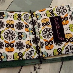 May include: A green fabric-covered journal with a white and black owl print. The journal has a black elastic closure and a small black label that says "Killa Birds".