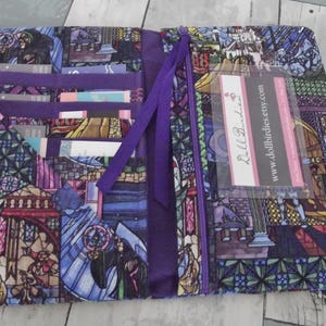 May include: Open wallet with a colorful stained-glass design featuring a rose, castle, and characters. The wallet has multiple card slots, a purple zipper, and a purple ribbon closure. A business card with the website "www.dollbirdies.etsy.com" is visible.