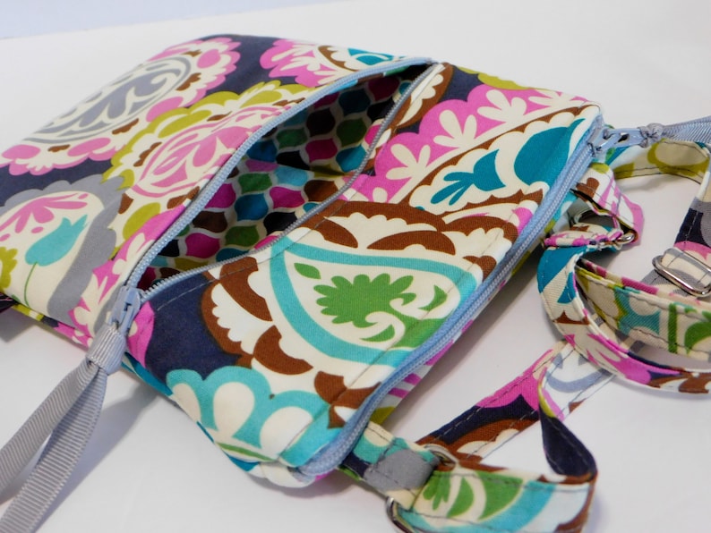 K&ouml;nnte beinhalten: Eine bunte Umh&auml;ngetasche mit Paisley-Muster, Rei&szlig;verschluss und verstellbarem grauen Schultergurt.