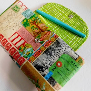 May include: A fabric pencil case with a vintage postage stamp design. The case is open, revealing a green and white patterned interior and a teal pen. The exterior features a collage of colorful stamps and labels.