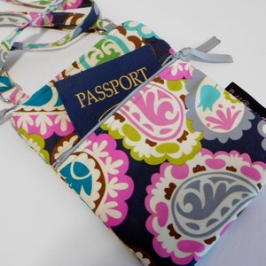 K&ouml;nnte beinhalten: Eine bunte Umh&auml;ngetasche mit Paisley-Muster, einer Rei&szlig;verschlusstasche und einem Reisepass im Inneren. Die Tasche hat einen grauen Riemen und ein kleines Etikett mit dem Text "Bella & Co."