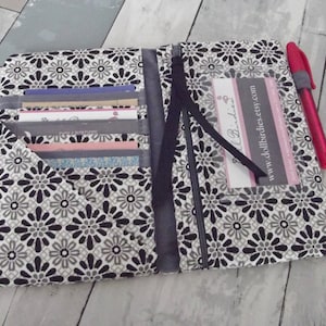 May include: A black and white floral fabric wallet with multiple card slots and a zipper closure. The wallet has a clear plastic window with a business card inside that reads "www.dollbirdies.etsy.com".