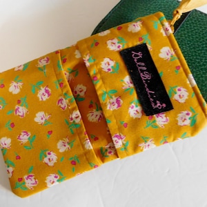 May include: A small yellow fabric pouch with a floral print and a black label that says "BellBindies".