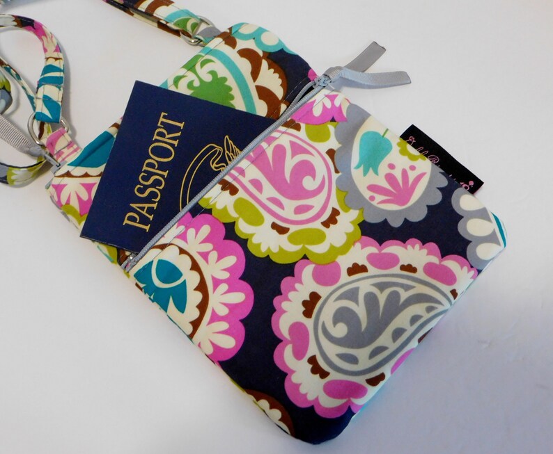K&ouml;nnte beinhalten: Eine kleine Umh&auml;ngetasche mit Paisley-Muster und Rei&szlig;verschluss. Die Tasche hat einen blauen Reisepass in der Rei&szlig;verschlusstasche. Die Tasche hat einen silbernen Rei&szlig;verschluss und einen silbernen Riemen.