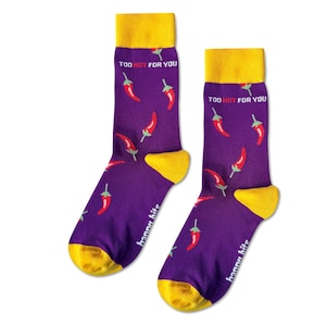 May include: A pair of purple socks with a yellow cuff and a red chilli pepper pattern. The socks have the text "Too Hot For You" printed on them.