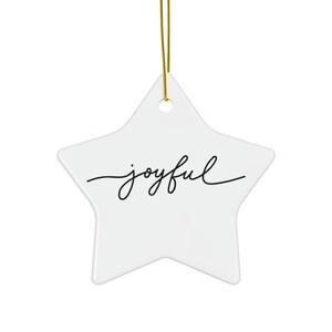 May include: A white star-shaped ornament with the word "joyful" in black script. The ornament is hanging by a gold string. The design is simple and elegant, suitable for holiday or everyday decor.
