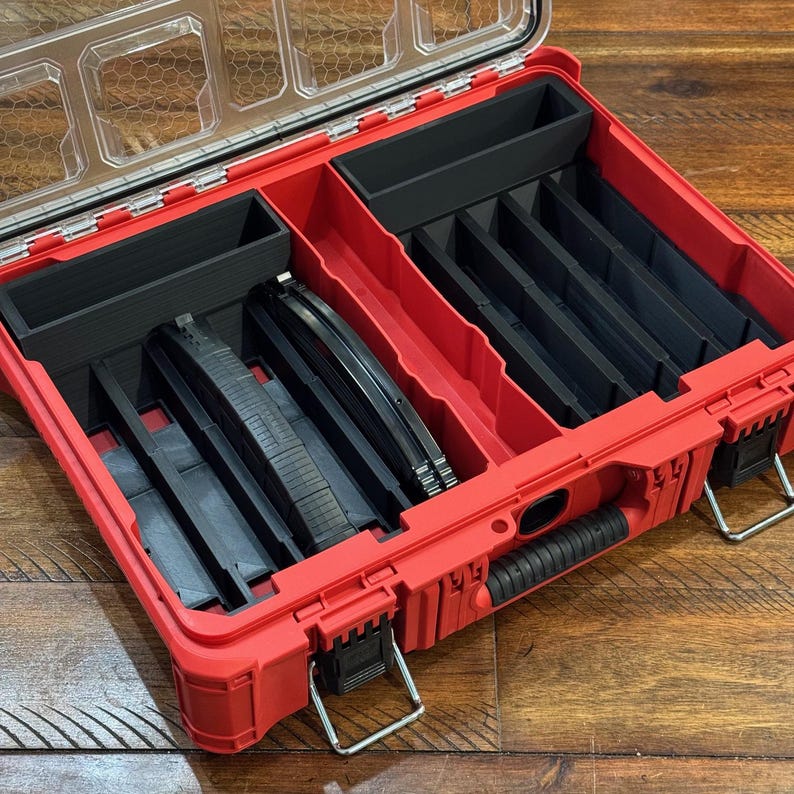 May include: A red plastic tool organizer with a clear lid, featuring multiple black compartments and dividers. The organizer has a black handle and metal latches. The interior contains various tools and accessories.