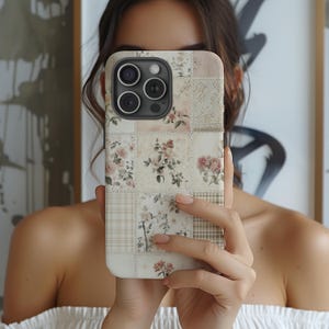 May include: A white iPhone case with a floral patchwork design. The case has a camera lens cutout and a white background.