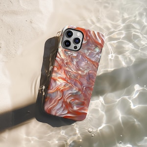 Peut inclure: Une coque de téléphone avec un motif tourbillonnant et iridescent dans des tons d'orange, de blanc et de rose. La coque a une découpe pour l'appareil photo avec trois objectifs.