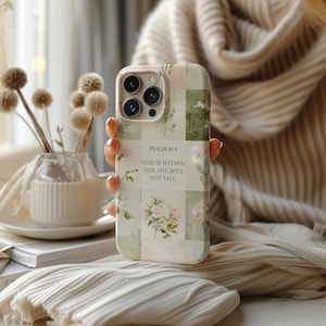 Pode incluir: Capa de telefone floral em tons pastel. A capa apresenta um design de patchwork com ilustrações botânicas e o texto "Salmo 46:5: Deus está nela, ela não cairá."