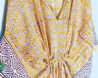 May include: Yellow and red patterned kaftan with a white trim. The kaftan has a V-neck and a tie at the waist. The fabric is soft and flowy.