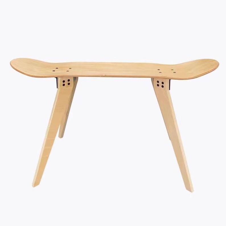 K&ouml;nnte beinhalten: Eine Holzbank aus einem Skateboard-Deck mit vier Beinen. Die Bank ist hellbraun und hat eine nat&uuml;rliche Holzoptik.