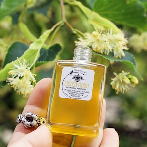 Peut inclure: Un petit flacon en verre de parfum botanique Linden Moon, un m&eacute;lange d'huile de jojoba biologique infus&eacute;e de plantes, d'huiles essentielles pures et d'absolues. La bouteille est &eacute;tiquet&eacute;e avec le nom de la marque "Phoeni" et le nom du produit "Linden Moon".