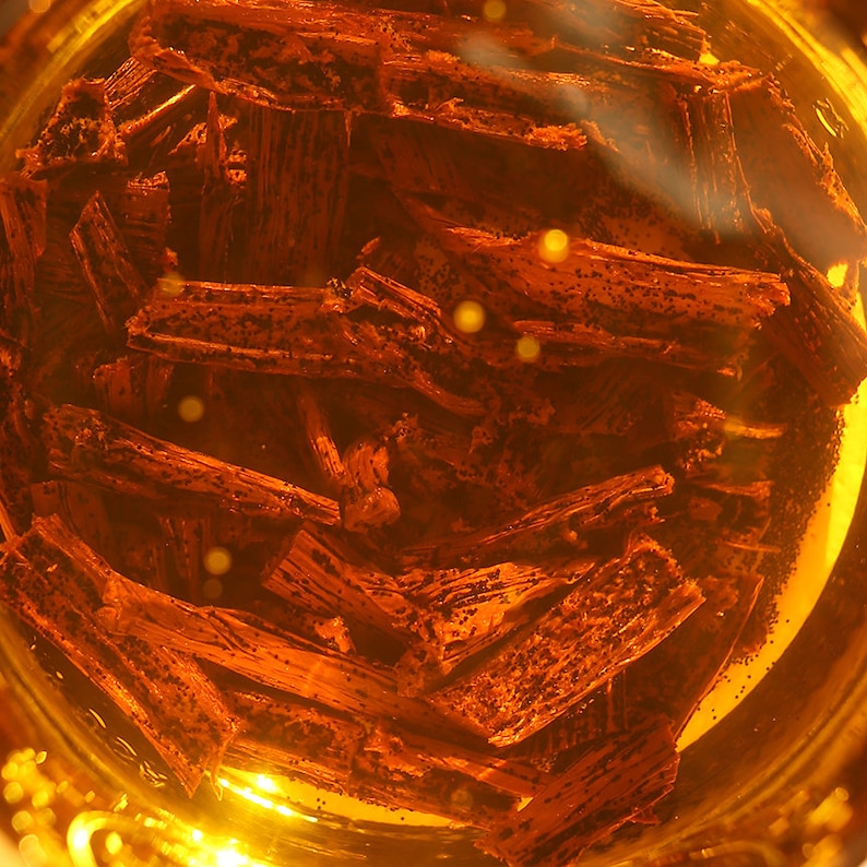 May include: Close-up of a glass jar filled with brown vanilla beans submerged in a golden liquid.