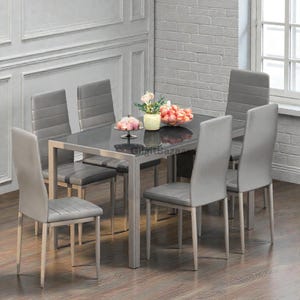 May include: A modern dining set featuring a rectangular black glass table and six gray upholstered chairs. The table has a silver metal frame. The chairs have a sleek design. A centerpiece of flowers and fruit decorates the table.