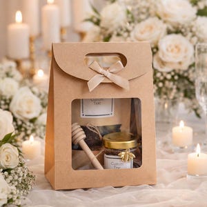 May include: A brown paper gift bag with a window, tied with a ribbon. Inside, a jar of honey with a gold lid and bee charm, a wooden honey dipper, and a tag that says "Custom Text". The background includes candles and flowers.