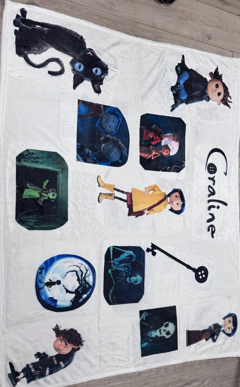 May include: White blanket featuring multiple images from the movie "Coraline." The images include a black cat, characters, and scenes from the film. The word "Coraline" is written in black script on the blanket.