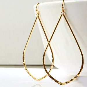 Puede incluir: Un par de pendientes de oro en forma de lágrima con textura martillada.