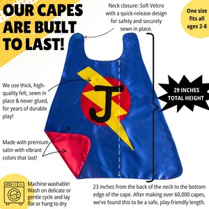 以下が含まれることがあります： 青いスーパーヒーローのマント。赤い裏地、黄色の稲妻と文字「J」が特徴です。マントの高さは73.66 cmで、首元はソフトベルクロ留めです。「私たちのマントは長持ちするように作られています！」と「洗濯機で洗えます！」というテキストがあります。